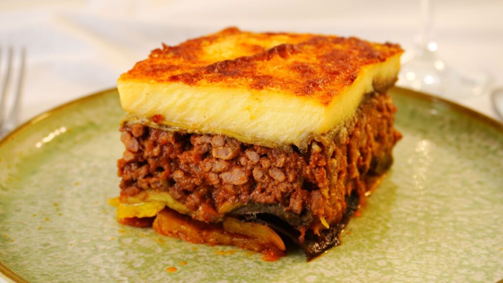 A piece of Greek Moussaka (eggplant casserole) on a green plate.