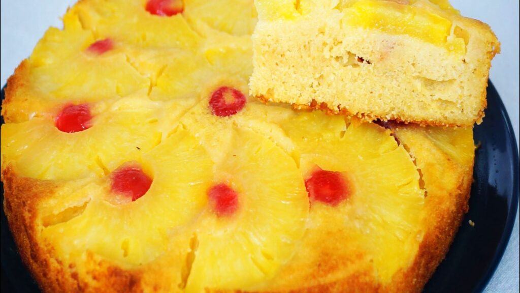 Pineapple upside-down cake with one slice cut and put on top of the cake.