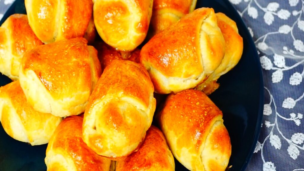Many small homemade mini bacon pies arranged on a dark blue plate.