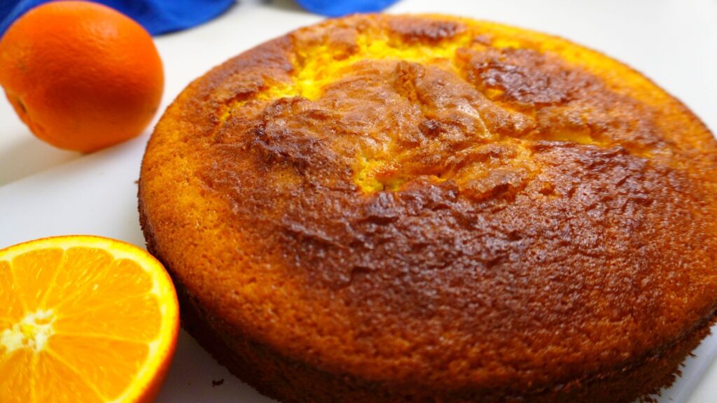 Orange cake with a few oranges next to it.